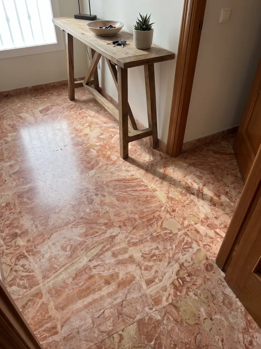 Piso de recibidor en placas grandes de mármol rosa Breccia Bohemien con luz natural: mezcla densa de fragmentos coral y beige claro en tonos salmón