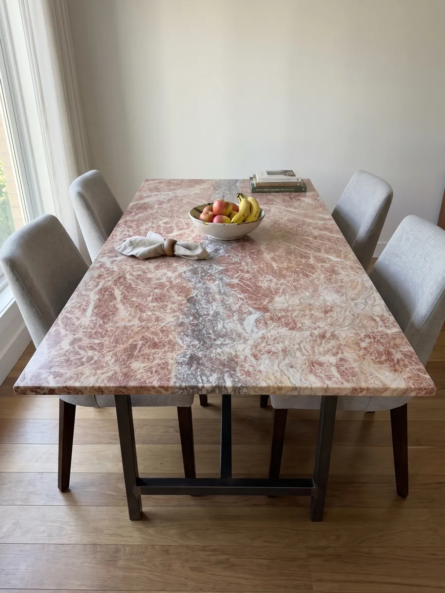 Mesa de comedor con cubierta de Mármol Rosa Peralba sobre base de acero: rosa rojizo con red de vetas blancas y una franja vertical gris violácea