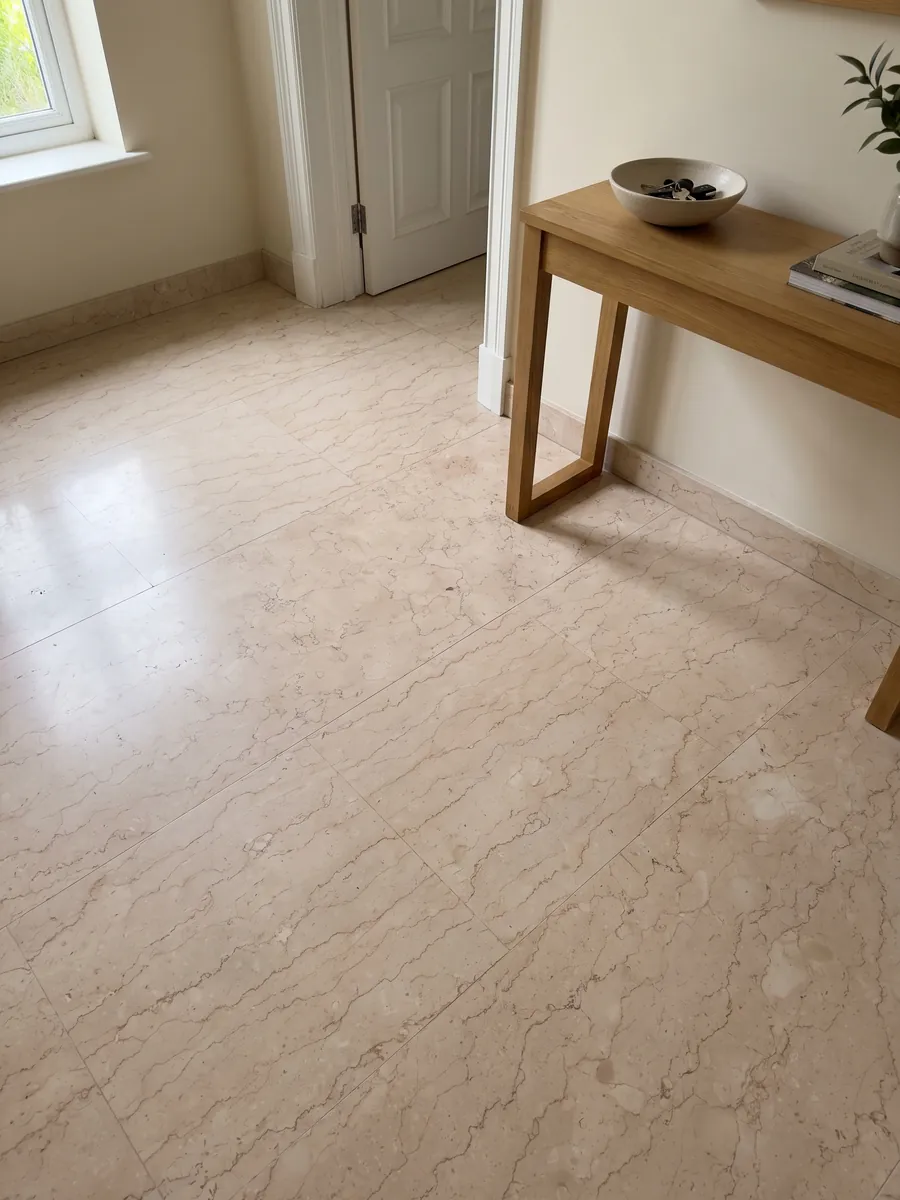 Piso de recibidor en placas grandes de Mármol Rosa Perlino con luz natural: beige rosado claro con líneas finas onduladas en red suave