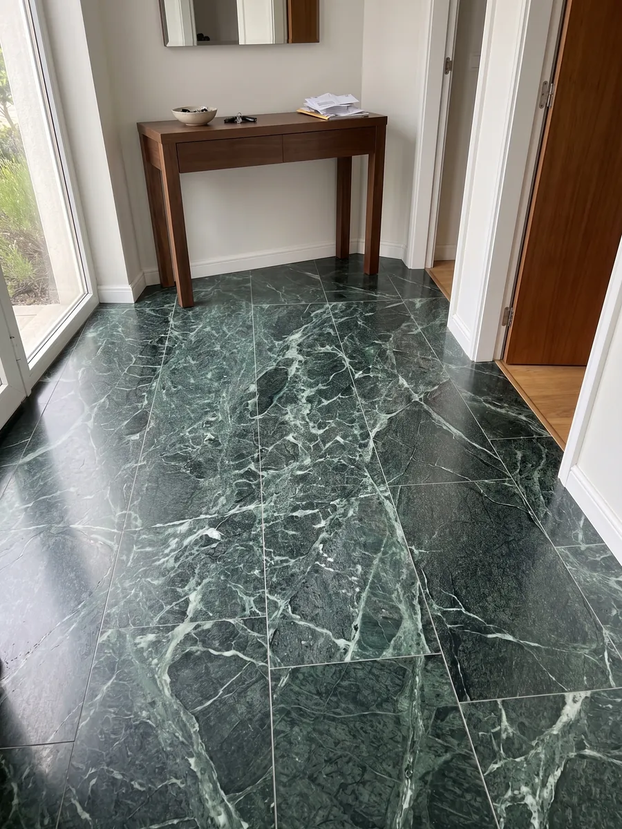 Piso de recibidor en placas grandes de Mármol Verde Alpi con luz natural: verde casi negro atravesado por una red tupida de vetas verde claro y blancas