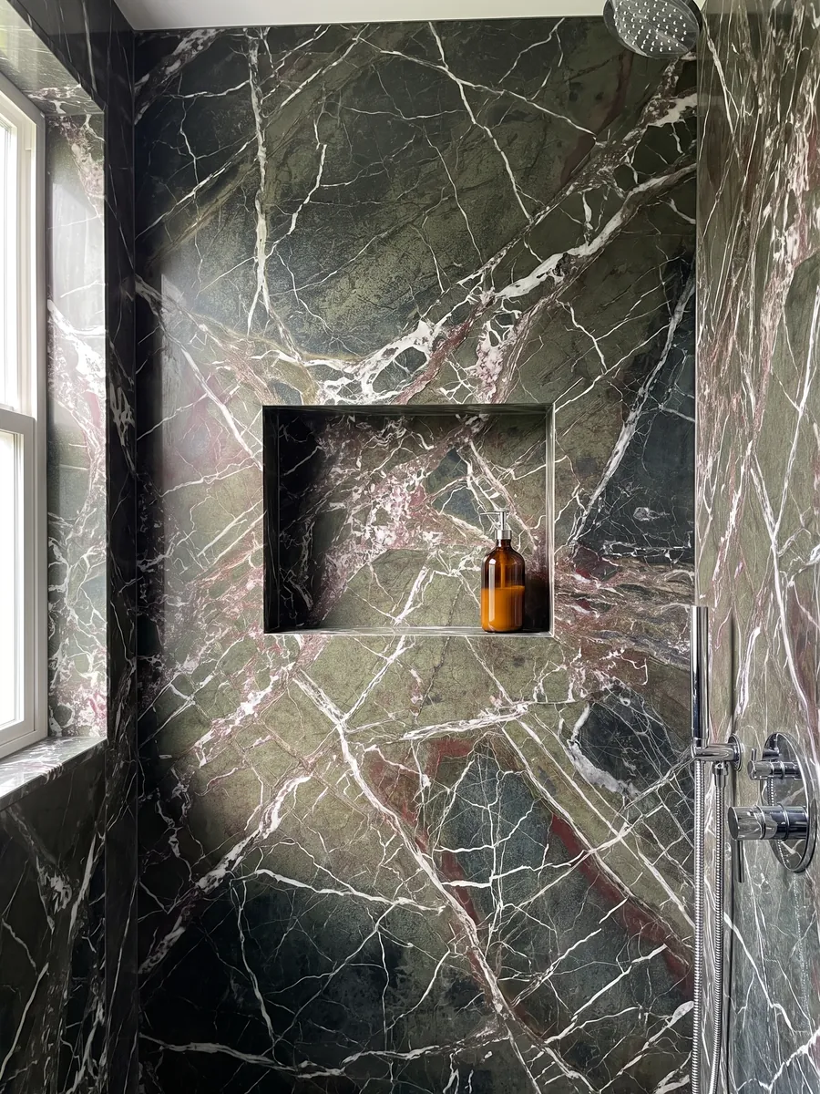 Ducha revestida con placas enteras de mármol verde Breccia Imperiale con nicho empotrado: verde oscuro con red de vetas blancas rectas y pequeños toques rojo vino