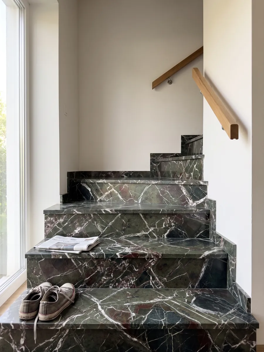 Escalera interior con peldaños de mármol verde Breccia Imperiale con pasamanos: verde oscuro con red de vetas blancas rectas y pequeños toques rojo vino
