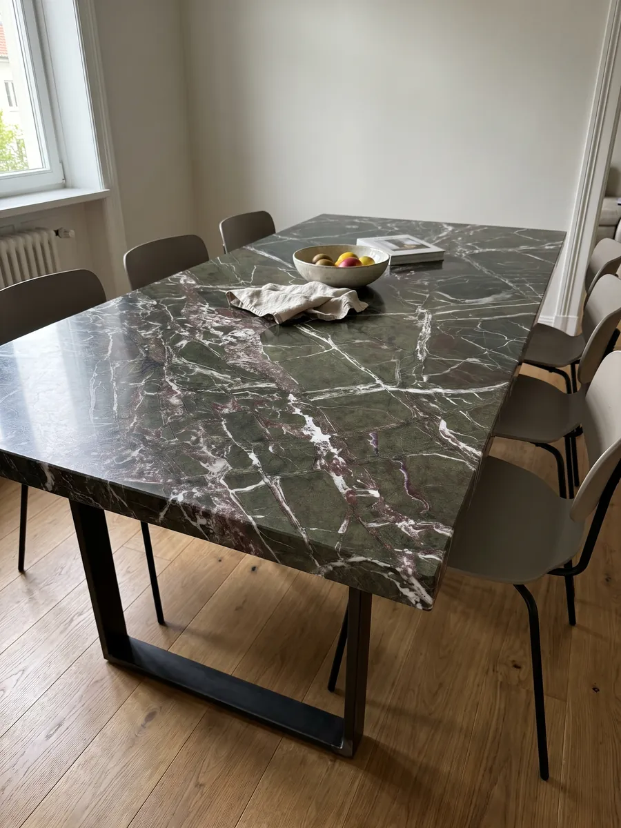 Mesa de comedor con cubierta de mármol verde Breccia Imperiale sobre base de acero: verde oscuro con red de vetas blancas rectas y pequeños toques rojo vino
