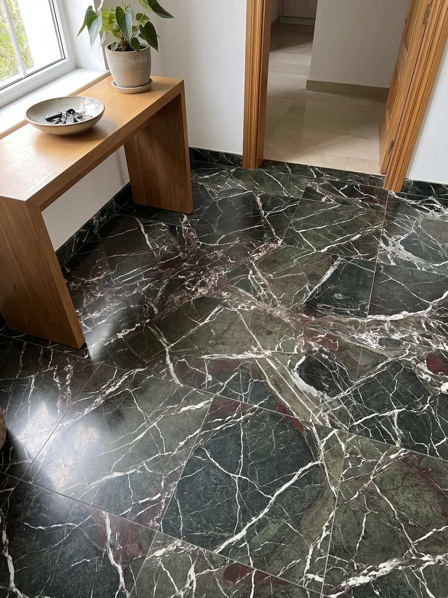 Piso de recibidor en placas grandes de mármol verde Breccia Imperiale con luz natural: verde oscuro con red de vetas blancas rectas y pequeños toques rojo vino
