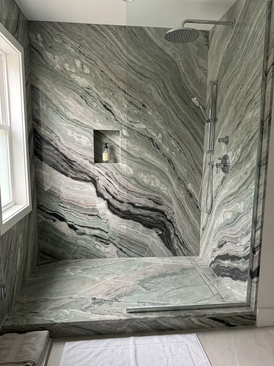 Ducha revestida con placas enteras de mármol verde Camellia Green con nicho empotrado: bandas finas onduladas verde grisáceo con una franja negra marcada abajo