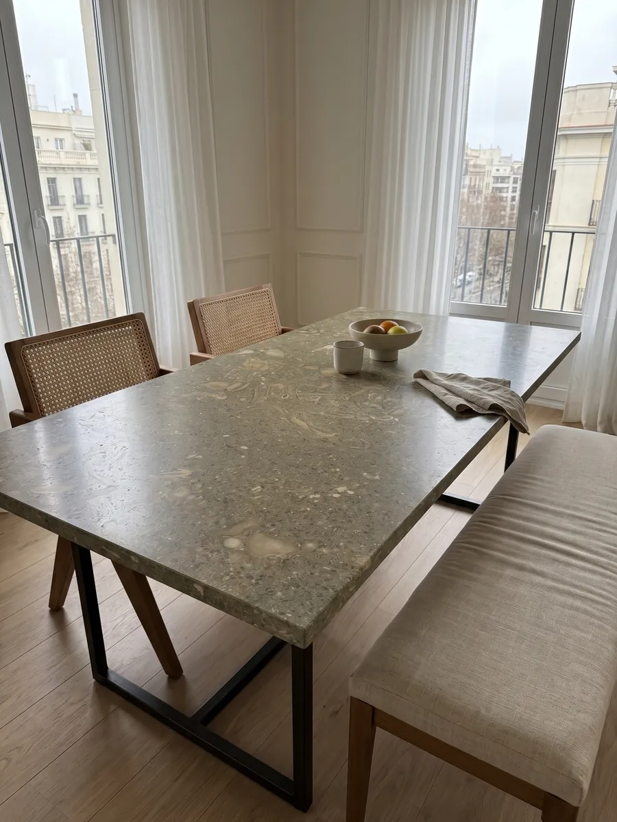 Mesa de comedor con cubierta de mármol verde Fossil Green sobre base de acero: verde oliva moteado con siluetas de conchas fósiles en tono más claro