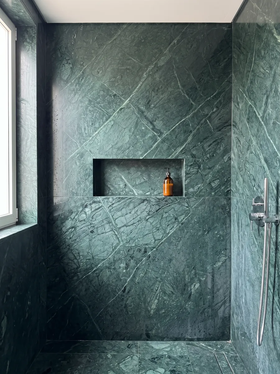 Ducha revestida con placas enteras de Mármol Verde Imperial con nicho empotrado: verde petróleo profundo con vetas finas más claras que cruzan en diagonal