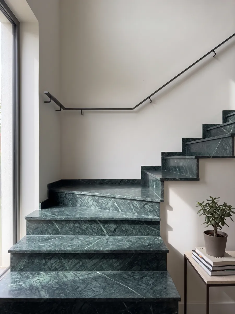 Escalera interior con peldaños de Mármol Verde Imperial con pasamanos: verde petróleo profundo con vetas finas más claras que cruzan en diagonal
