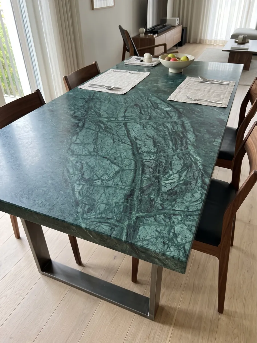 Mesa de comedor con cubierta de Mármol Verde Imperial sobre base de acero: verde petróleo profundo con vetas finas más claras que cruzan en diagonal