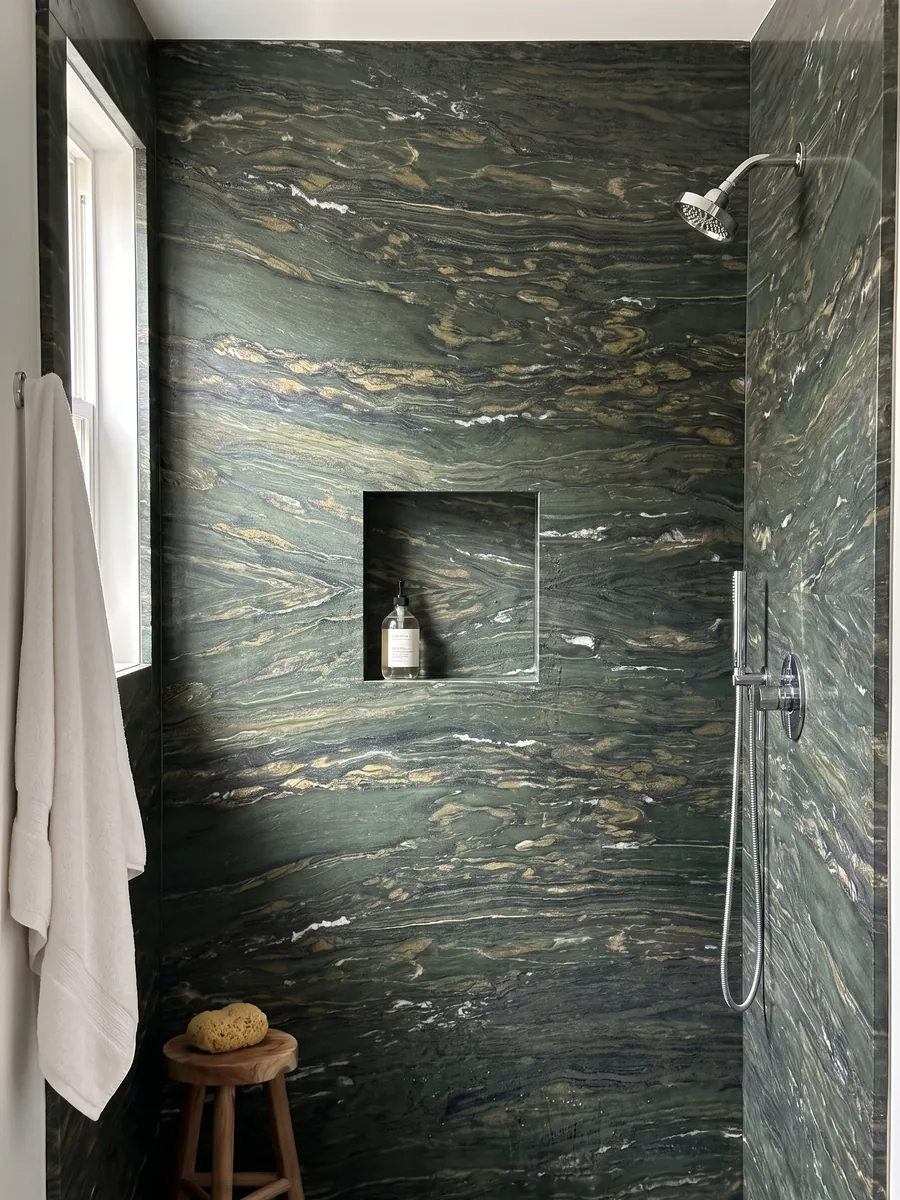 Ducha revestida con placas enteras de Mármol Verde Pavone con nicho empotrado: verde profundo con trazos dorados y blancos que fluyen en horizontal