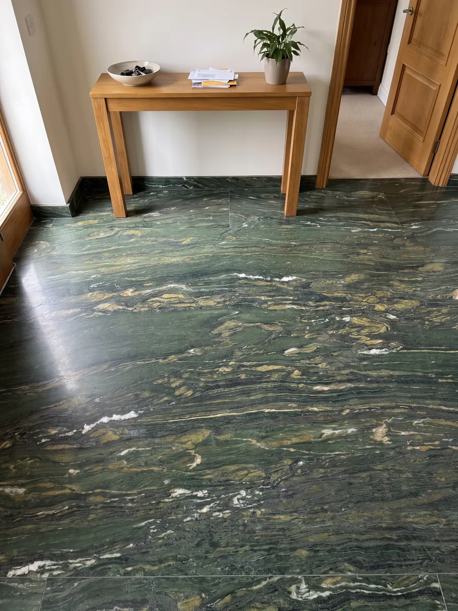 Piso de recibidor en placas grandes de Mármol Verde Pavone con luz natural: verde profundo con trazos dorados y blancos que fluyen en horizontal
