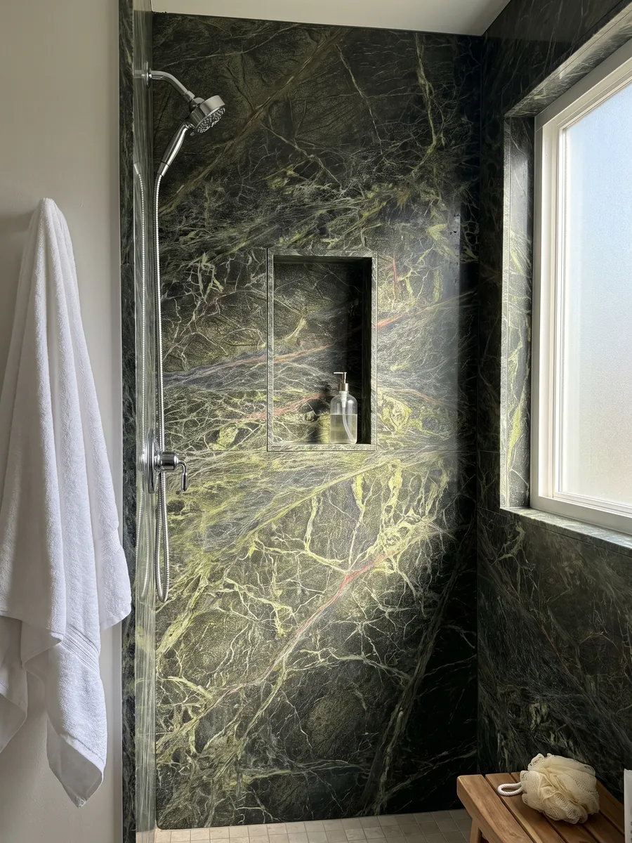 Ducha revestida con placas enteras de mármol verde Rainforest Green con nicho empotrado: verde oscuro cubierto por una red densa de vetas verde amarillento