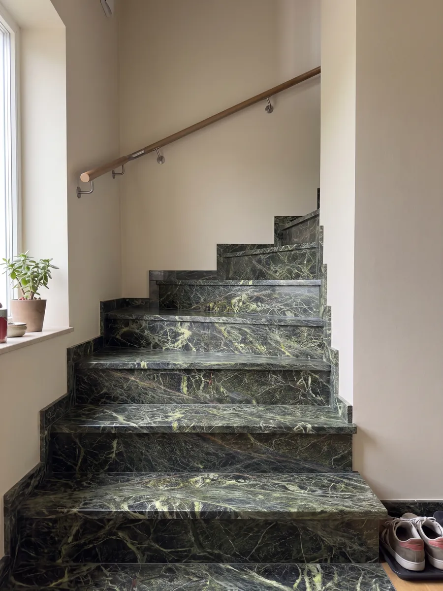 Escalera interior con peldaños de mármol verde Rainforest Green con pasamanos: verde oscuro cubierto por una red densa de vetas verde amarillento