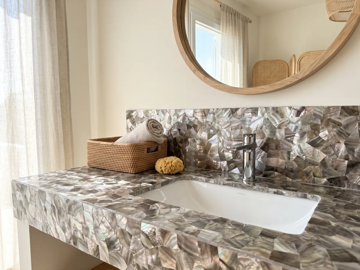 Cubierta de lavabo y pared de baño en Nácar de Concha Marrón con lavamanos blanco y grifería cromada: piezas de nácar gris pardo y plateado con brillo irisado