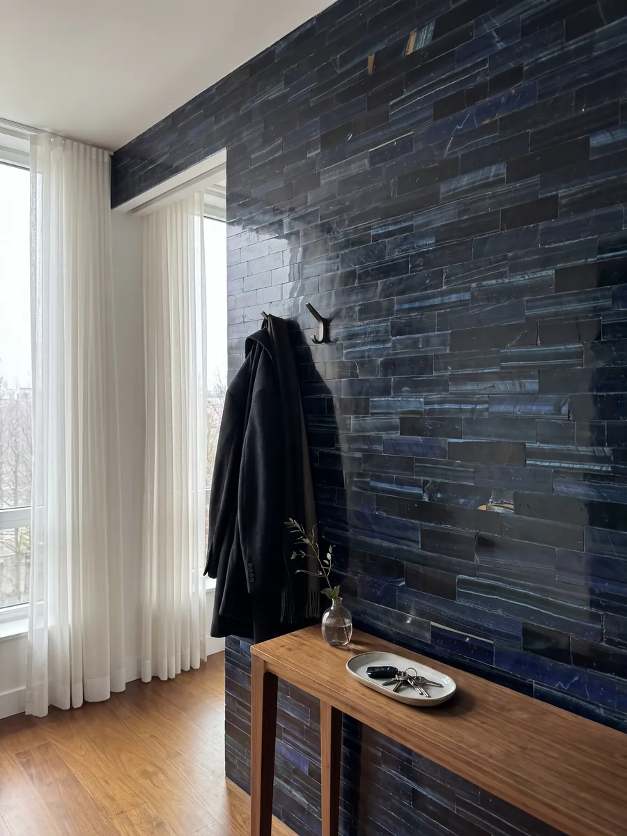 Pared de recibidor revestida con Ojo de Tigre Azul Extra con consola estrecha: listones horizontales azul marino casi negro con reflejos azules