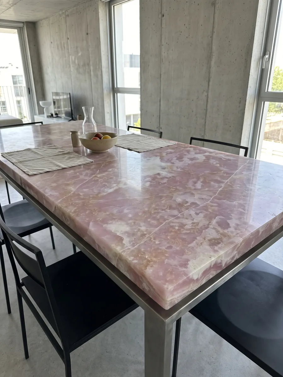 Mesa de comedor con cubierta de Ónix Rosa sobre base de acero: rosa lila con nubes blancas y líneas blancas finas que la cruzan