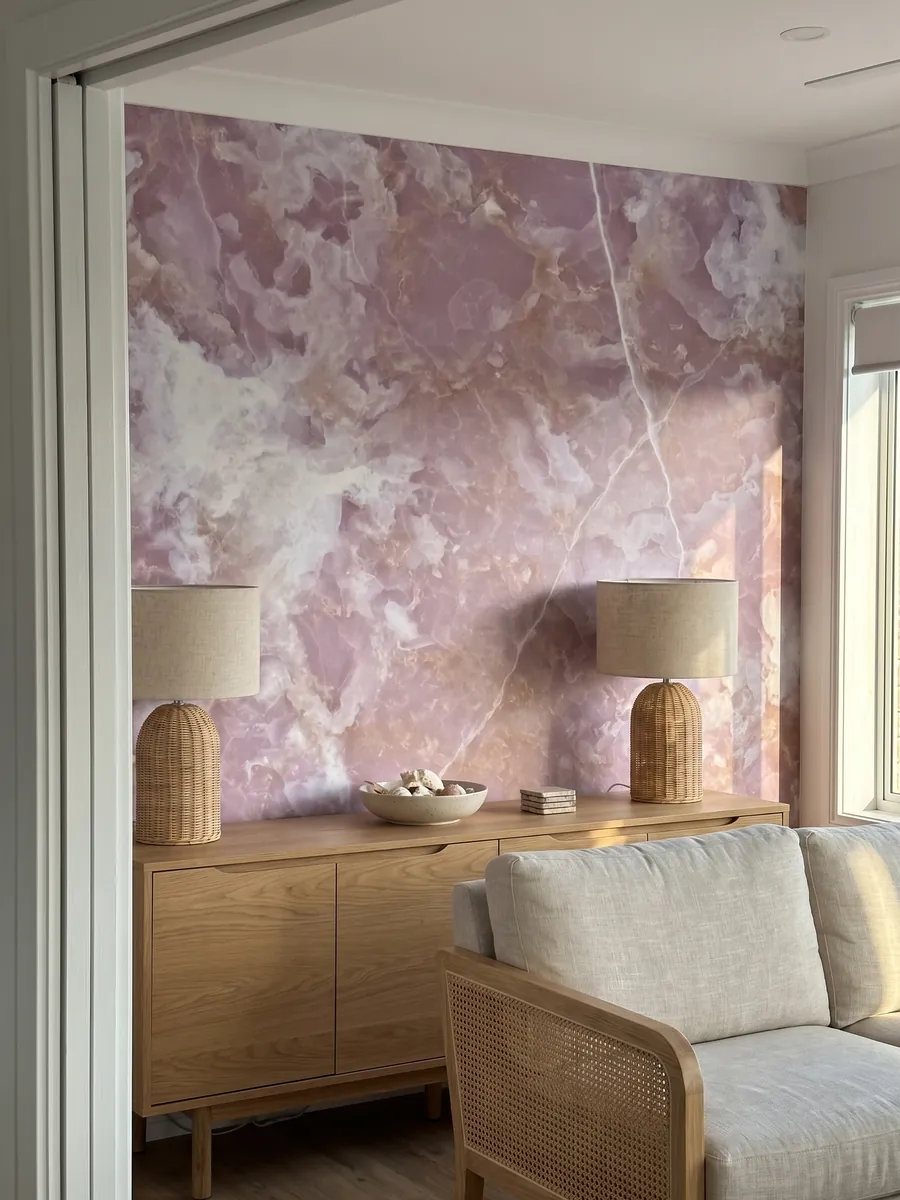 Pared de acento revestida con Ónix Rosa sobre un mueble bajo de madera: rosa lila con nubes blancas y líneas blancas finas que la cruzan