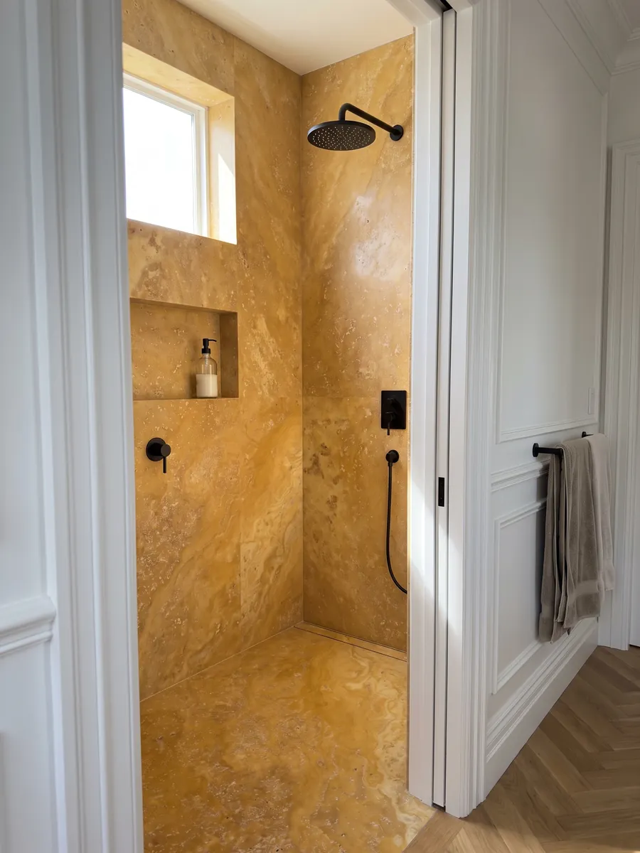 Ducha revestida con placas enteras de Travertino Amarillo con nicho empotrado: ocre dorado cálido con poros pequeños y nubes suaves de tono