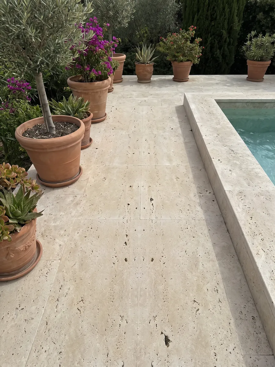Piso de terraza y borde de piscina en travertino beige Clásico con macetas: beige con agujeros oscuros alineados en vertical; el dibujo se ve simétrico como en espejo
