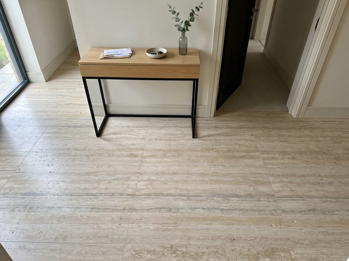 Piso de recibidor en placas grandes de travertino gris Ocean Silver con luz natural: franjas horizontales finas beige y grises con algunos poros