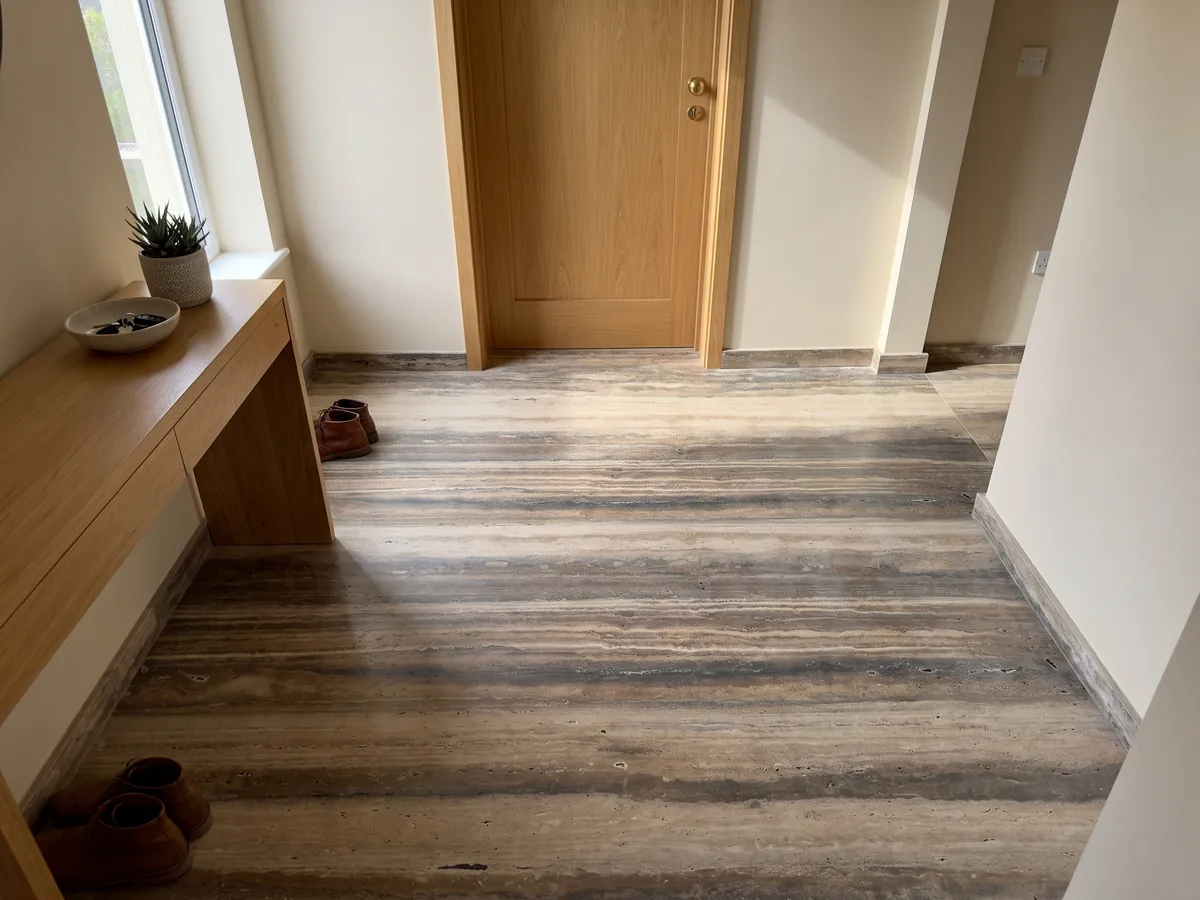 Piso de recibidor en placas grandes de travertino marrón Oscuro Silver con luz natural: franjas horizontales marrones y beige muy marcadas a lo largo de la placa