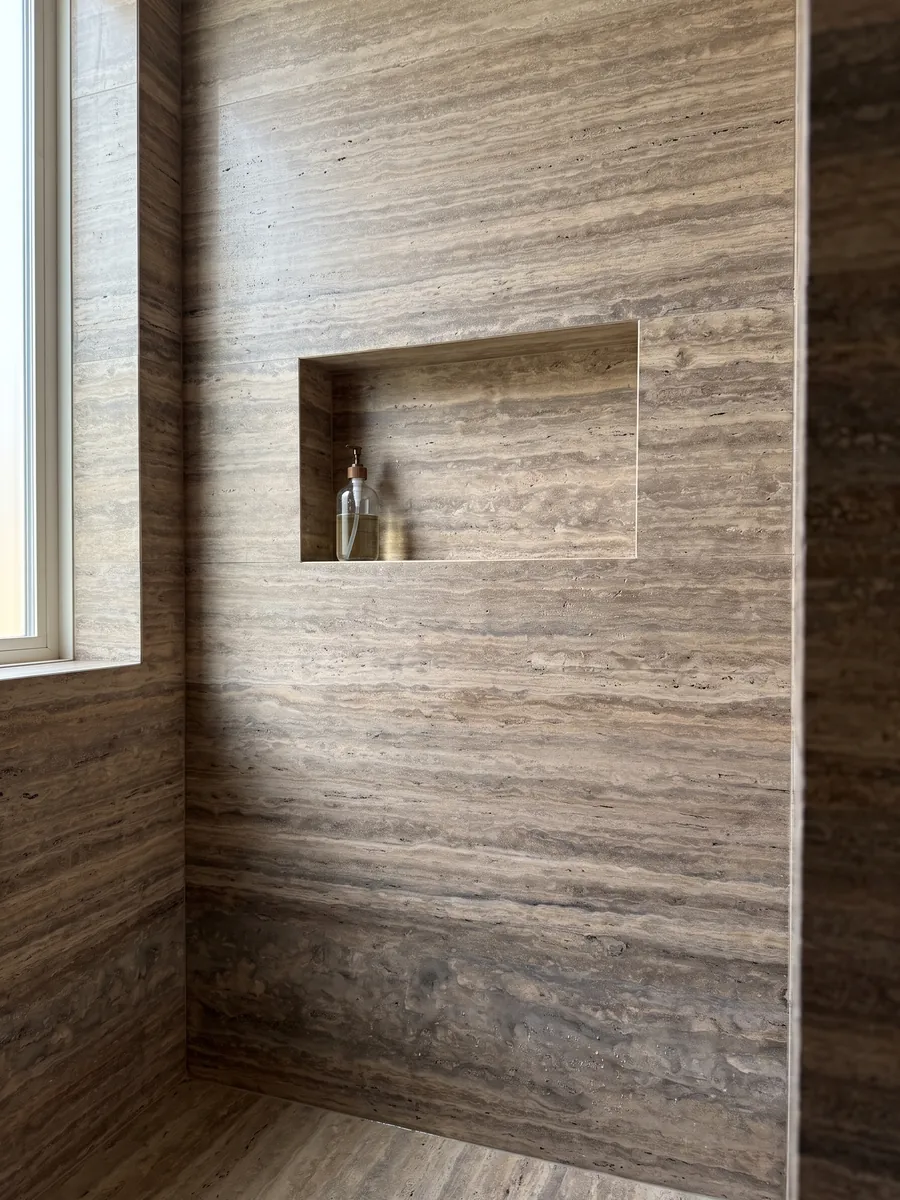 Ducha revestida con placas enteras de travertino marrón Pantheon con nicho empotrado: marrón con franjas horizontales finas y paralelas más claras