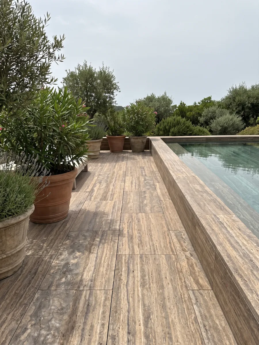 Piso de terraza y borde de piscina en travertino marrón Pantheon con macetas: marrón con franjas horizontales finas y paralelas más claras