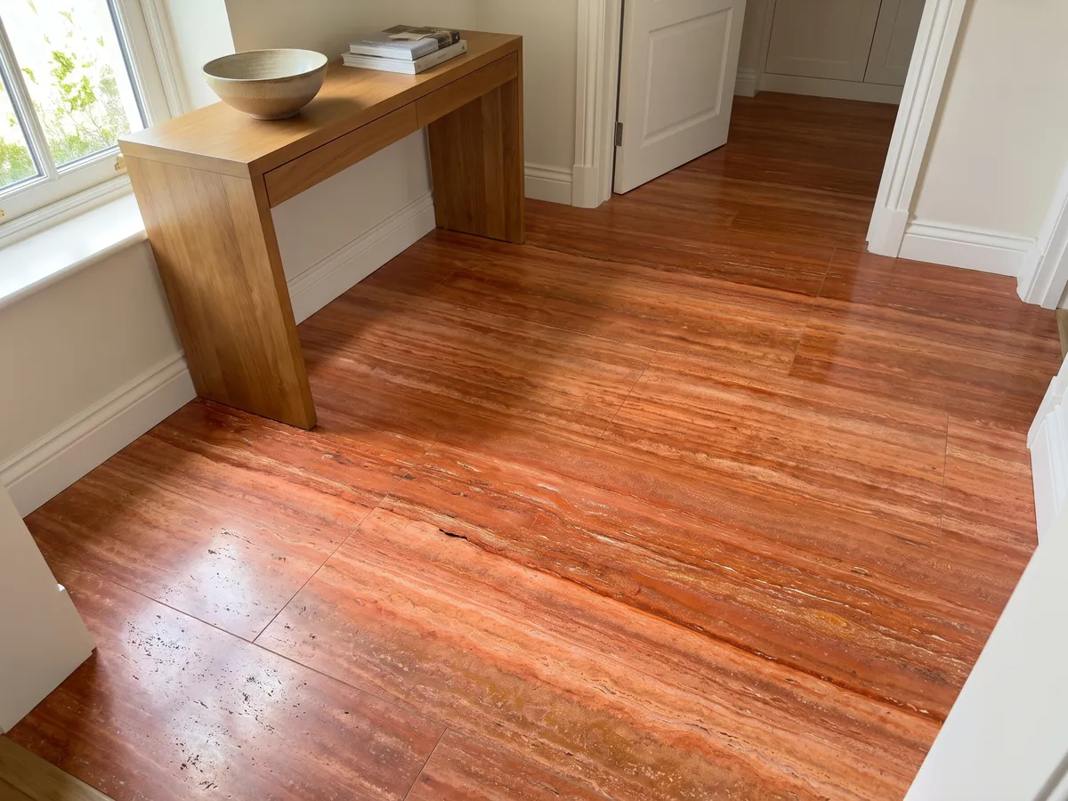 Piso de recibidor en placas grandes de Travertino Rojo con luz natural: rojo anaranjado intenso en franjas horizontales con líneas crema finas