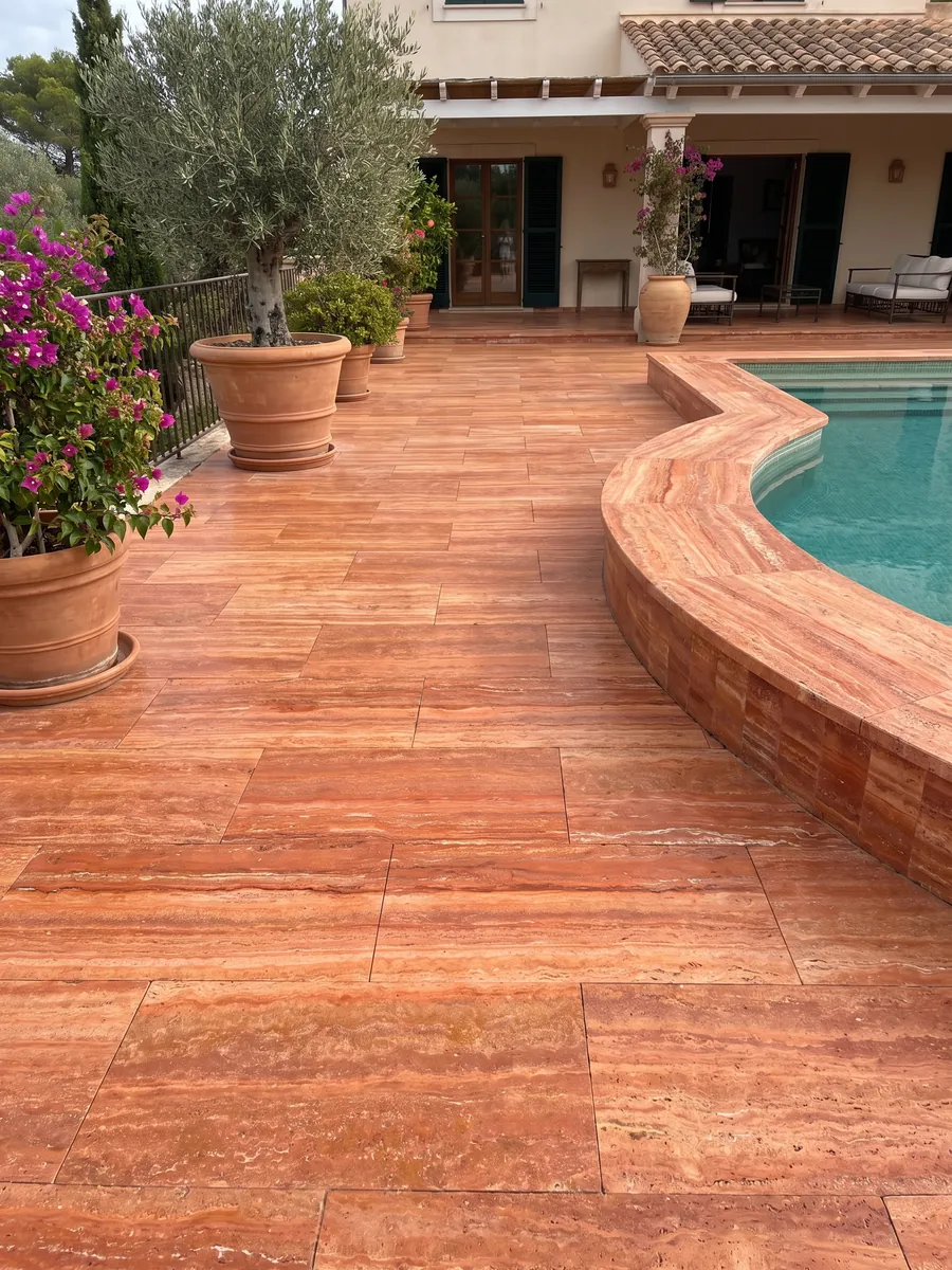 Piso de terraza y borde de piscina en Travertino Rojo con macetas: rojo anaranjado intenso en franjas horizontales con líneas crema finas