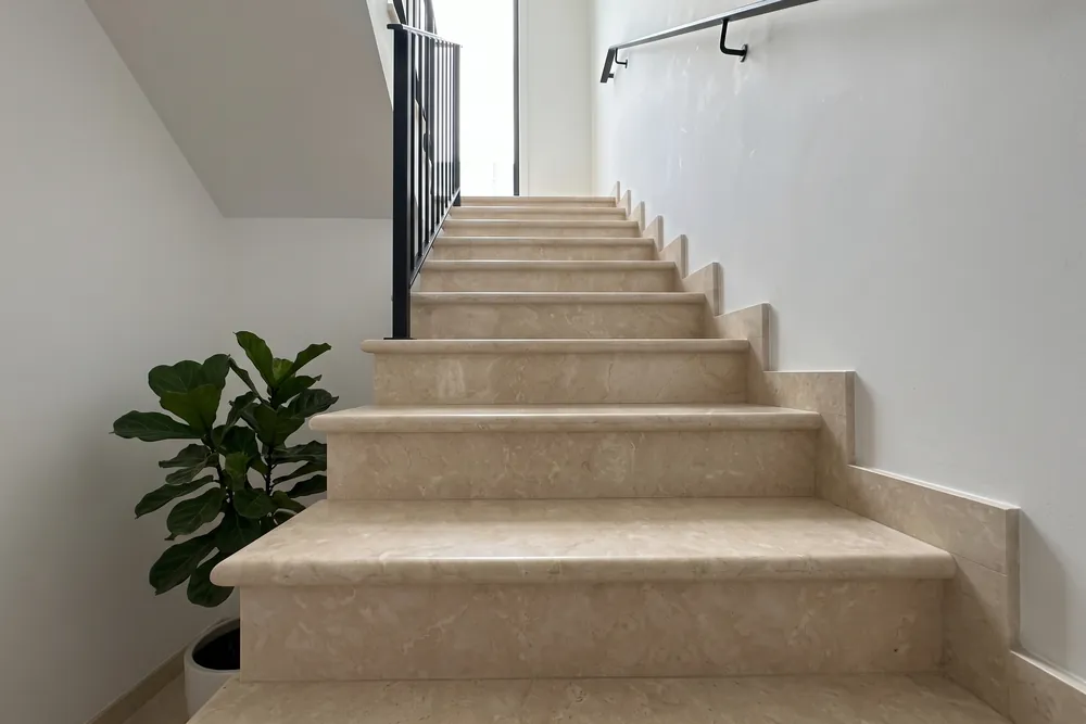 Escalera interior con peldaños de mármol Botticino