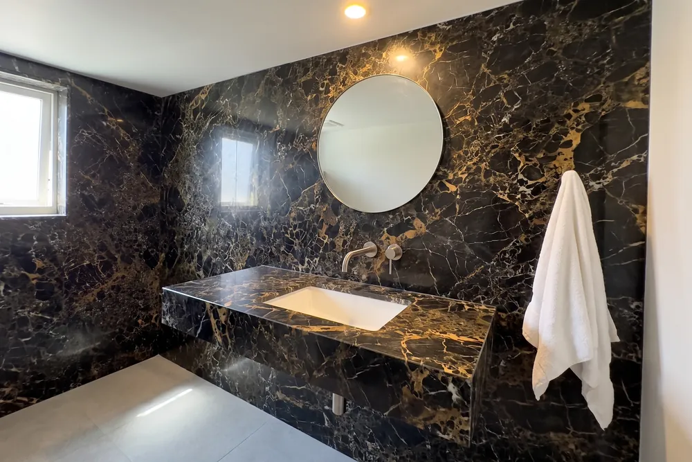 Baño con lavabo volado y pared de mármol Portoro