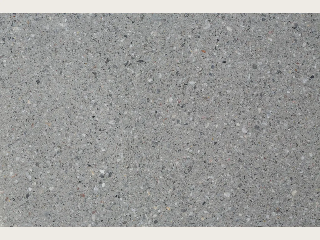 Placa de Mármol Sintético Fior di Pesco Grey con Cemento: fondo gris medio con fragmentos blancos y oscuros estilo terrazo