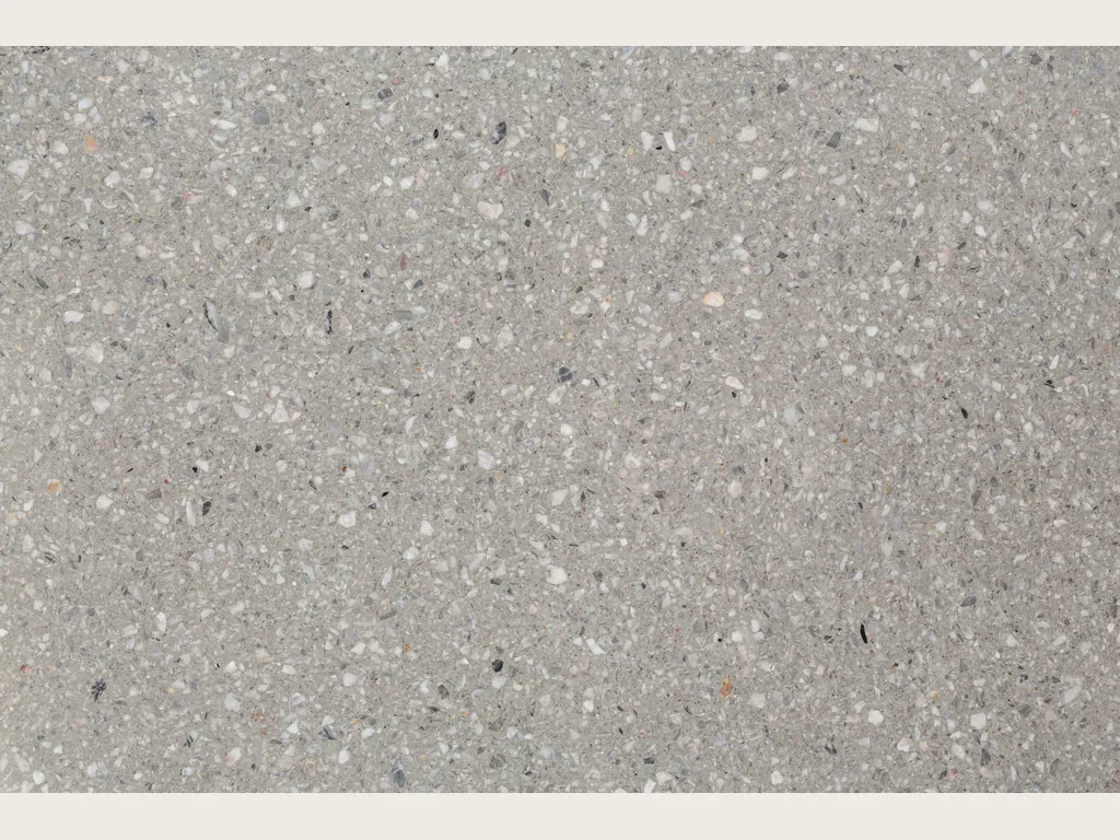 Placa de Mármol Sintético Fior di Pesco Grey con Resina: fondo gris claro con fragmentos blancos pequeños y puntos oscuros