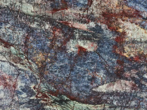Detalle de la Cuarcita Blue Luise: vetas rojo óxido, crema y verde sobre el pulido brillante