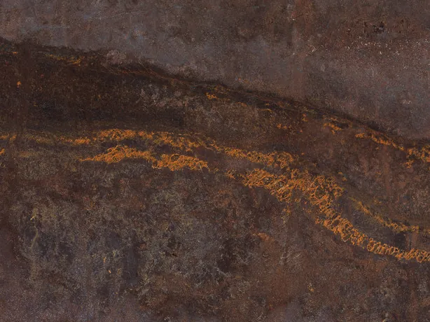 Detalle de la Cuarcita Bronzite: trazos y puntos naranja dorado sobre la banda más oscura del marrón chocolate