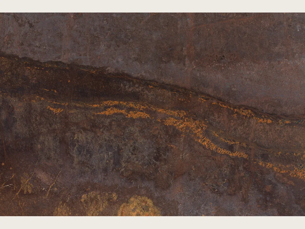 Placa de cuarcita marrón Bronzite: fondo marrón chocolate con banda horizontal más oscura salpicada de destellos naranja dorado