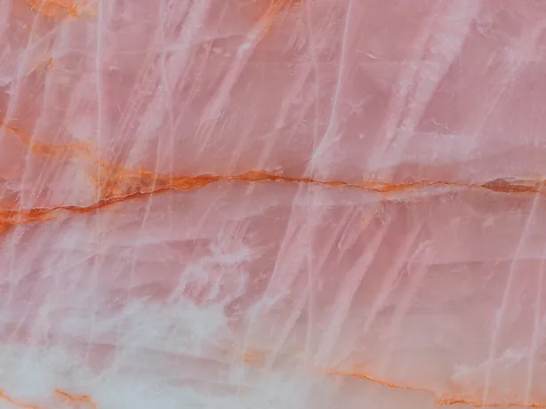 Detalle de la Cuarcita Cristallo Rosa: vetas naranja rojizas y trazos blancos sobre el fondo rosa salmón