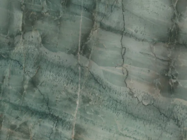 Detalle de la Cuarcita da Vinci: cruce de vetas verde oscuro y bandas claras sobre el brillo del pulido