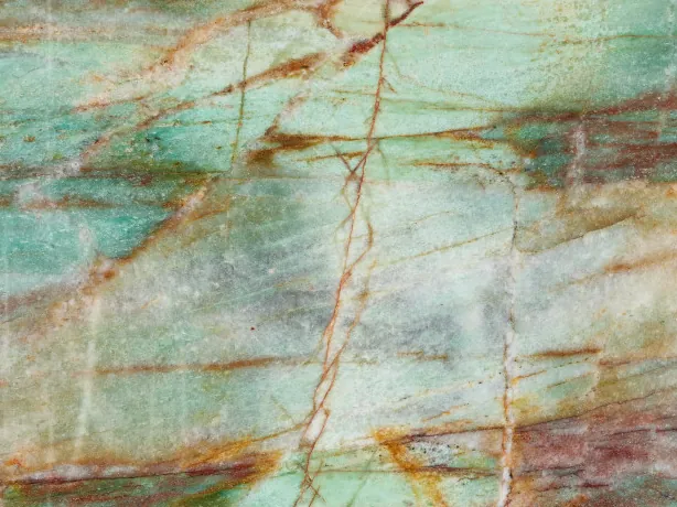 Detalle de la Cuarcita Green Luise: vetas rojo óxido y ocre sobre zonas turquesa y blancas, acabado pulido