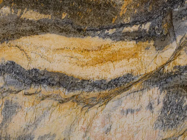 Detalle de la Cuarcita Jacaranda: ondas mostaza y gris oscuro con brillo de pulido