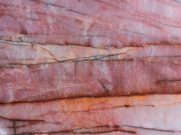 Detalle de la Cuarcita Juliet: vetas horizontales rojo óxido y naranja sobre el rosa