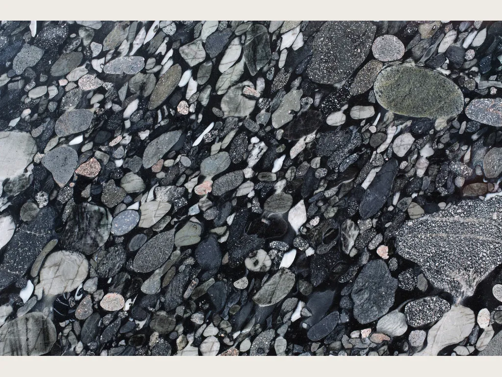 Placa de cuarcita negra Marinace Black: cantos rodados grises, blancos y rosados sobre fondo negro