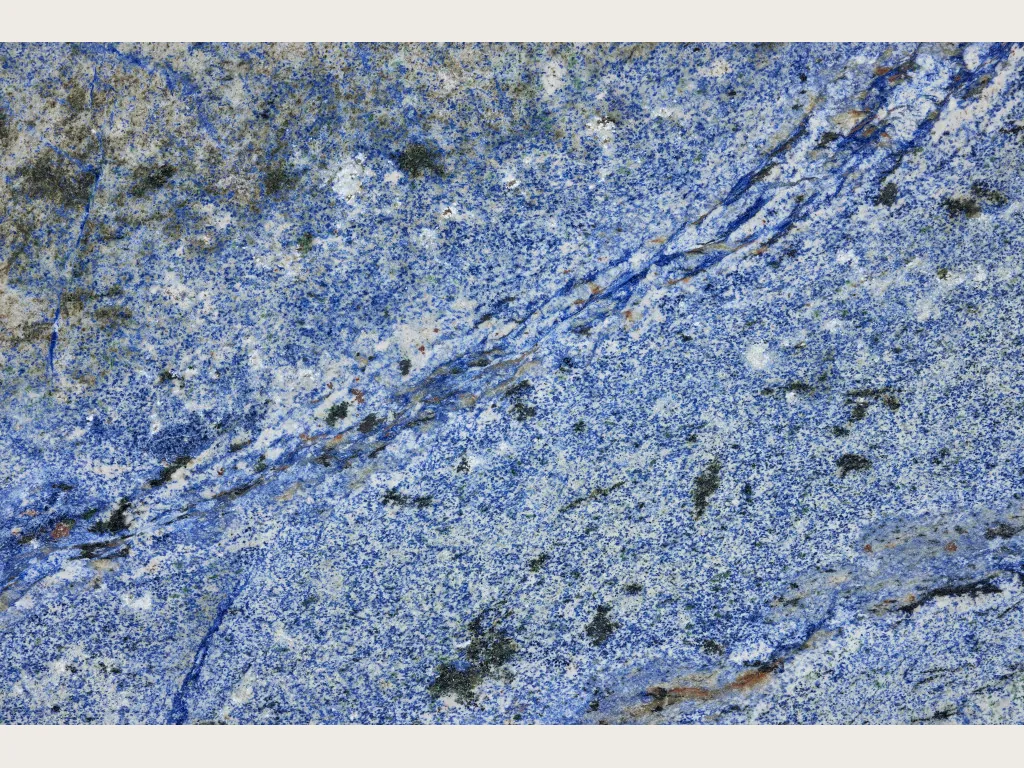 Placa de Granito Azul Bahia: fondo azul cobalto granulado con zonas blancas y una franja diagonal azul oscuro