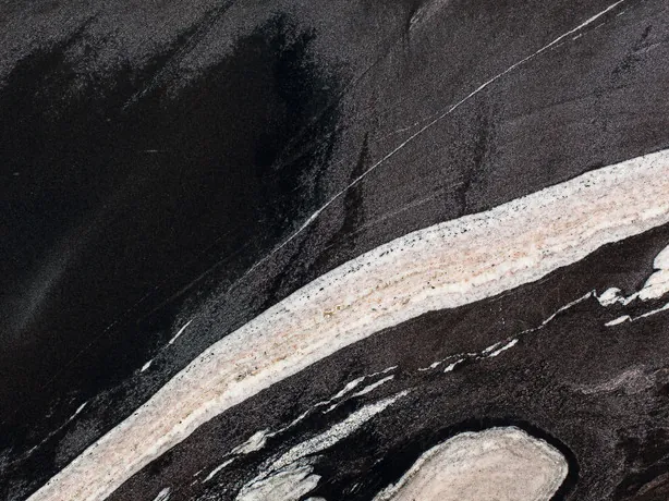 Detalle de la placa de granito negro Copacabana: brillo del pulido y contraste de la banda crema sobre el negro