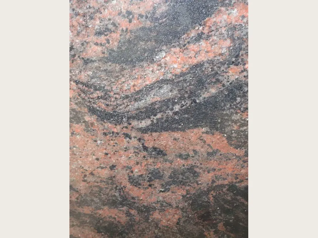 Placa de granito rojo Indian Aurora: bandas onduladas de coral, gris y negro en diagonal sobre fondo gris oscuro