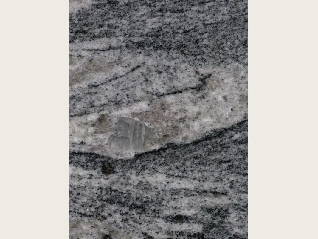 Placa de granito gris Piracema White: bandas onduladas de gris y blanco en horizontal con un gran fragmento claro
