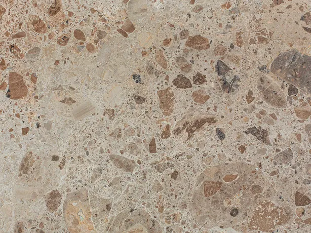 Detalle del Mármol Ambrosia: fragmentos marrones y óxido de varios tamaños sobre el fondo beige