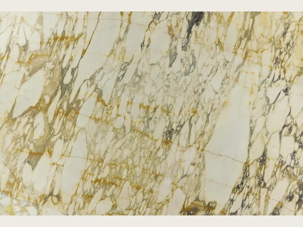 Placa de mármol beige Calacatta Monet Gold: fragmentos crema dentro de una red densa de vetas doradas y gris oscuro