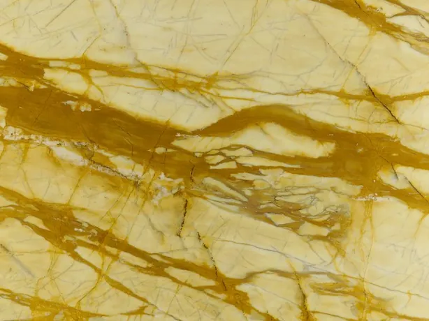 Detalle del Calacatta Siena: vetas ocre gruesas que se enredan sobre el fondo amarillo pálido