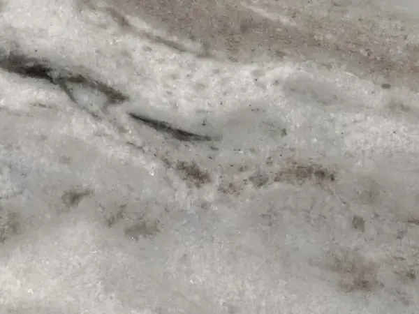 Placa de Mármol Fantasy Brown: fondo gris claro, nubes blancas, franjas difusas en diagonal suave y trazos marrón grisáceo